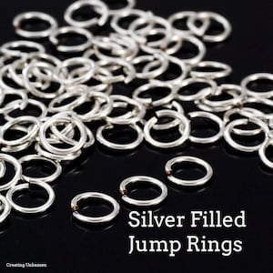 Puede incluir: Un montón de anillos de salto rellenos de plata. Los anillos son pequeños y redondos, y son perfectos para la elaboración de joyas.