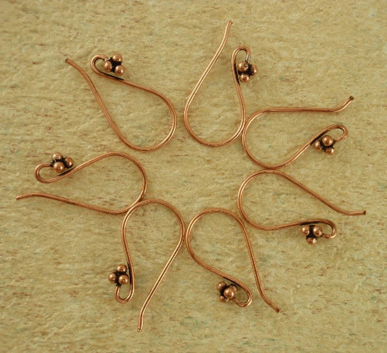 May include: Six copper earring hooks with a cluster of three small balls at the end of each hook.