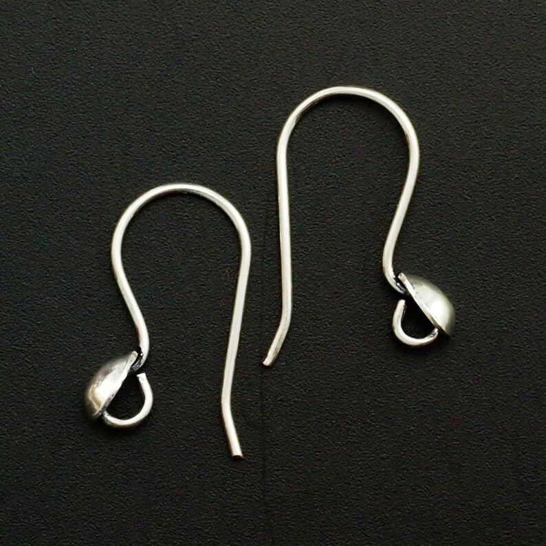 May include: Two silver earring hooks with a small round ball at the end of each hook.