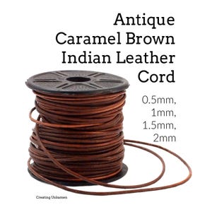 May include: A spool of antique caramel brown Indian leather cord. The text on the image reads: Antique Caramel Brown Indian Leather Cord, 0.5mm, 1mm, 1.5mm, 2mm, and Creating Unkamen. The cord is wrapped around a black plastic spool.