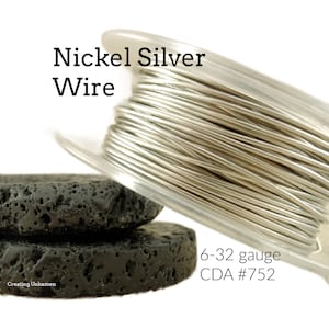 May include: A spool of silver-colored nickel wire, 6-32 gauge, CDA #752. The wire is wound around a clear plastic spool and is sitting on two black lava rock coasters.