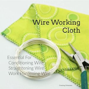 Può includere: Un tessuto verde con cerchi bianchi e una bobina di filo d'argento in cima. Il testo "Wire Working Cloth" è scritto in nero sul tessuto. Il testo "Essential For Conditioning Wire Straightening Wire Work Hardening Wire" è scritto in nero sotto la bobina. Un paio di pinze con manici verdi è sul lato destro dell'immagine.