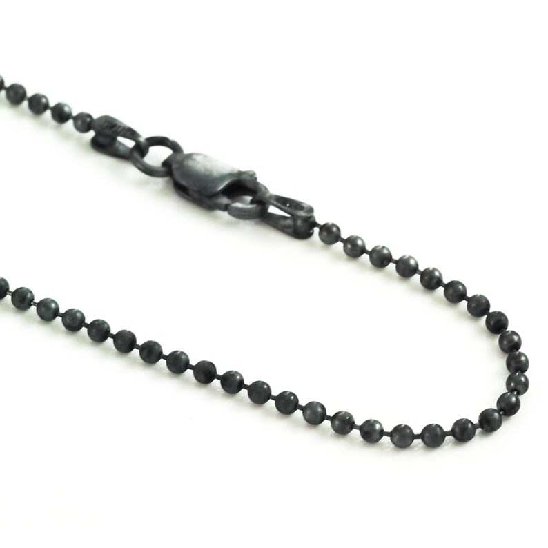 May include: A black chain necklace with a ball chain style. The chain has a lobster clasp closure.