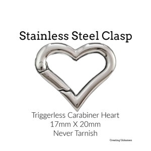 Könnte beinhalten: Herzförmiger, auslösefreier Karabinerverschluss aus Edelstahl. Er misst 17 mm x 20 mm und wird als "Nie anlaufen" beworben.