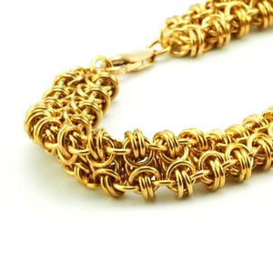 May include: A gold chain bracelet with a woven design. The bracelet is made of metal and has a clasp closure.