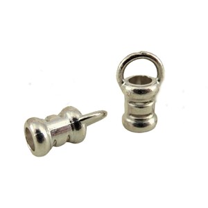 May include: Two silver-colored metal eyelet findings. One is upright with a loop, the other is horizontal with a pin. These findings are used in jewelry making and crafts.