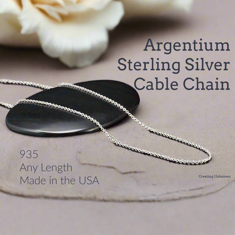 May include: A silver cable chain necklace made of 935 sterling silver. The chain is on a black stone surface. The text "Argentium Sterling Silver Cable Chain" and "935 Any Length Made in the USA" is visible in the image.