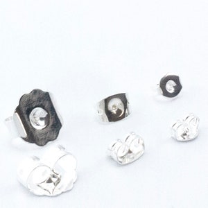May include: Four silver earring backs, two are butterfly backs and two are push backs.