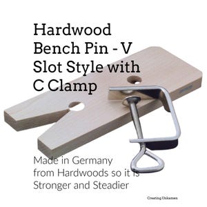 May include: A light-colored hardwood bench pin featuring a V-slot design and a circular hole, accompanied by a silver-toned metal C-clamp. The text on the image reads: Hardwood Bench Pin - V Slot Style with C Clamp. Made in Germany from Hardwoods so it is Stronger and Steadier.