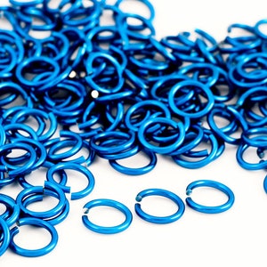 May include: A large pile of bright blue metal jump rings, with a few rings separated from the pile in the foreground.