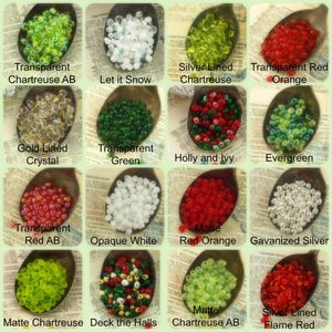 May include: Assortment of glass beads in various colors and finishes, including transparent, opaque, and metallic. The beads are arranged in a grid pattern on a spoon-shaped surface. The beads are labeled with names such as "Transparent Chartreuse AB", "Let it Snow", "Silver Lined Chartreuse", "Transparent Red Orange", "Matte Chartreuse AB", and "Silver Lined Flame Red".
