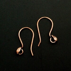 May include: Two rose gold earring hooks with a small ball at the end of each hook.