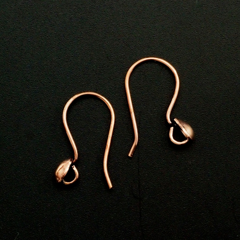 May include: Two rose gold earring hooks with a small ball at the end of each hook.