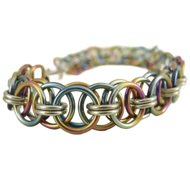 May include: A multi-colored metal bracelet with a chain link design. The bracelet is made of silver, gold, blue, and pink metal.