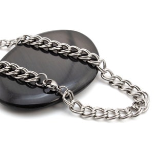 May include: A silver chain necklace with a lobster clasp closure. The chain is made of multiple strands of linked metal.