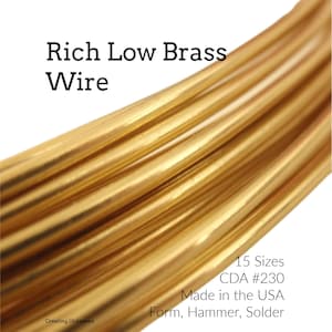May include: A coil of shiny gold-colored Rich Low Brass Wire. The text on the image reads: Rich Low Brass Wire, 15 Sizes, CDA #230, Made in the USA, Form, Hammer, Solder, and Creating Unkamen. The wire has a smooth, metallic, cylindrical surface.