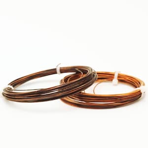 May include: Two spools of copper wire, one dark brown and one light brown, are wrapped around each other. The wire is thin and appears to be used for jewelry making.