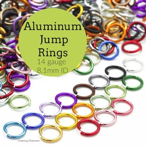 May include: A collection of multicolored aluminum jump rings in various shades including red, blue, green, purple, yellow, and black. The rings are 14 gauge with an 8.1mm inner diameter. A green circular overlay displays the text Aluminum Jump Rings.