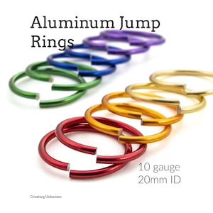 May include: A collection of colorful aluminum jump rings arranged in two rows. The rings are 10 gauge with a 20mm ID. The colors include purple, blue, green, gold, orange, and red. The text "Aluminum Jump Rings" and "10 gauge 20mm ID" is visible.