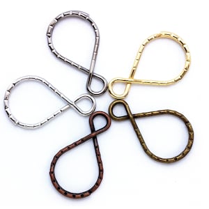 May include: Four metal key rings in different finishes: silver, gold, bronze, and copper. Each ring is shaped like a teardrop with a small loop at the top.