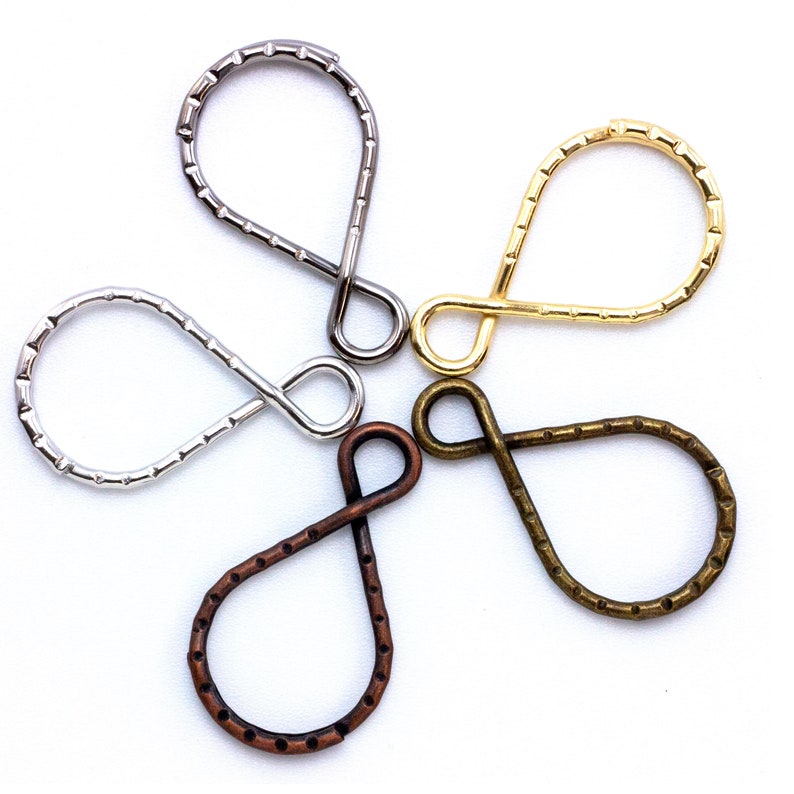 May include: Four metal key rings in different finishes: silver, gold, bronze, and copper. Each ring is shaped like a teardrop with a small loop at the top.