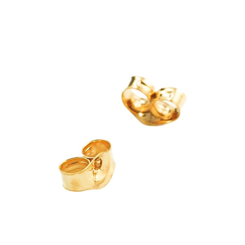 May include: Two gold-colored metal earring backs with a rounded, open-ended design. These small, circular components feature a smooth, reflective surface and are shaped to securely hold an earring post in place during regular daily wear.
