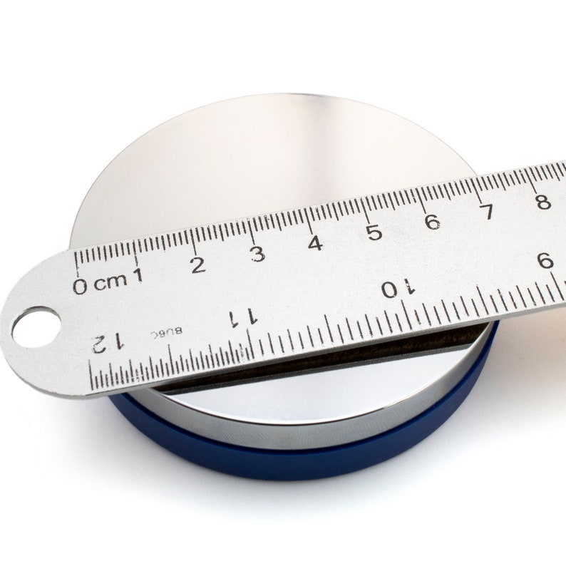 May include: A silver metal disc with a blue base is measured with a ruler. The ruler shows measurements in inches and centimeters. The disc is approximately 4 inches in diameter.