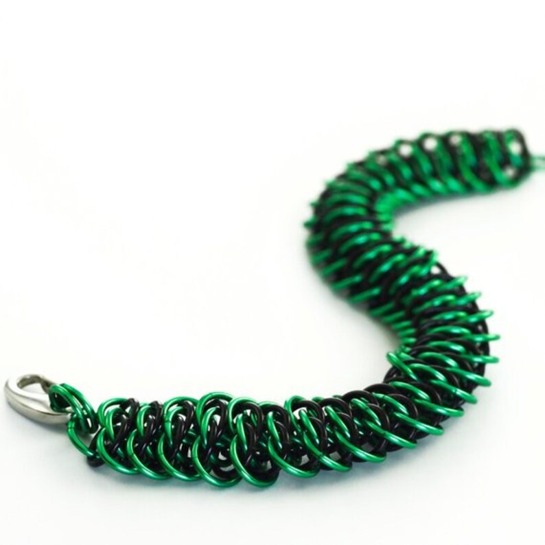May include: A black and green chainmail bracelet with a silver clasp.