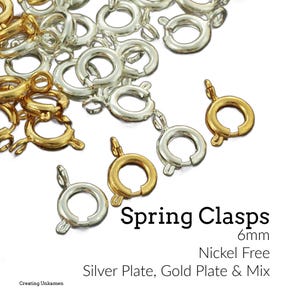 Puede incluir: Primer plano de cierres de resorte en tonos plateados y dorados. Los cierres miden 6 mm y no contienen níquel. El texto en la imagen dice "Spring Clasps" y "Silver Plate, Gold Plate & Mix."