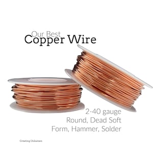 May include: Two spools of shiny, metallic copper wire wound around white plastic bobbins. The text reads: Our Best Copper Wire, 2-40 gauge, Round, Dead Soft, Form, Hammer, Solder, and Creating Unkamen. The wire has a smooth, reflective surface.