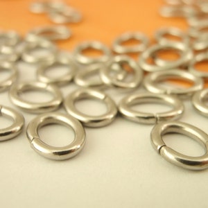 K&ouml;nnte beinhalten: Nahaufnahme eines Stapels silberner Sprungringe. Die Ringe sind oval geformt und haben eine glatte, gl&auml;nzende Oberfl&auml;che.