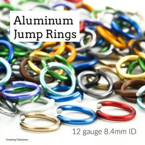 May include: A close-up of a pile of colorful aluminum jump rings. The rings are 12 gauge and have an inside diameter of 8.4mm. The rings are in various colors, including red, blue, green, gold, and silver.