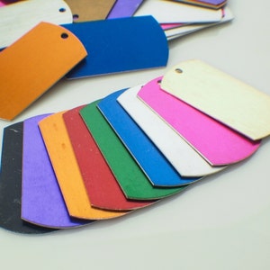 May include: A set of 10 colorful metal tags in various shades of blue, green, red, orange, purple, pink, and white. The tags are arranged in a fan shape, with the white tag at the top and the black tag at the bottom.
