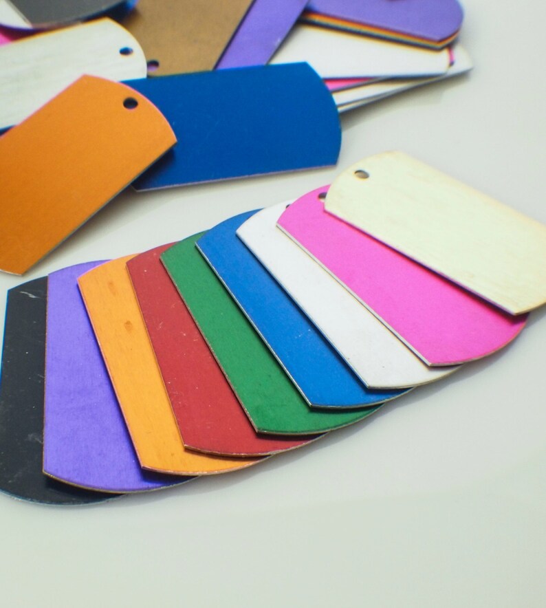 May include: A set of 10 colorful metal tags in various shades of blue, green, red, orange, purple, pink, and white. The tags are arranged in a fan shape, with the white tag at the top and the black tag at the bottom.