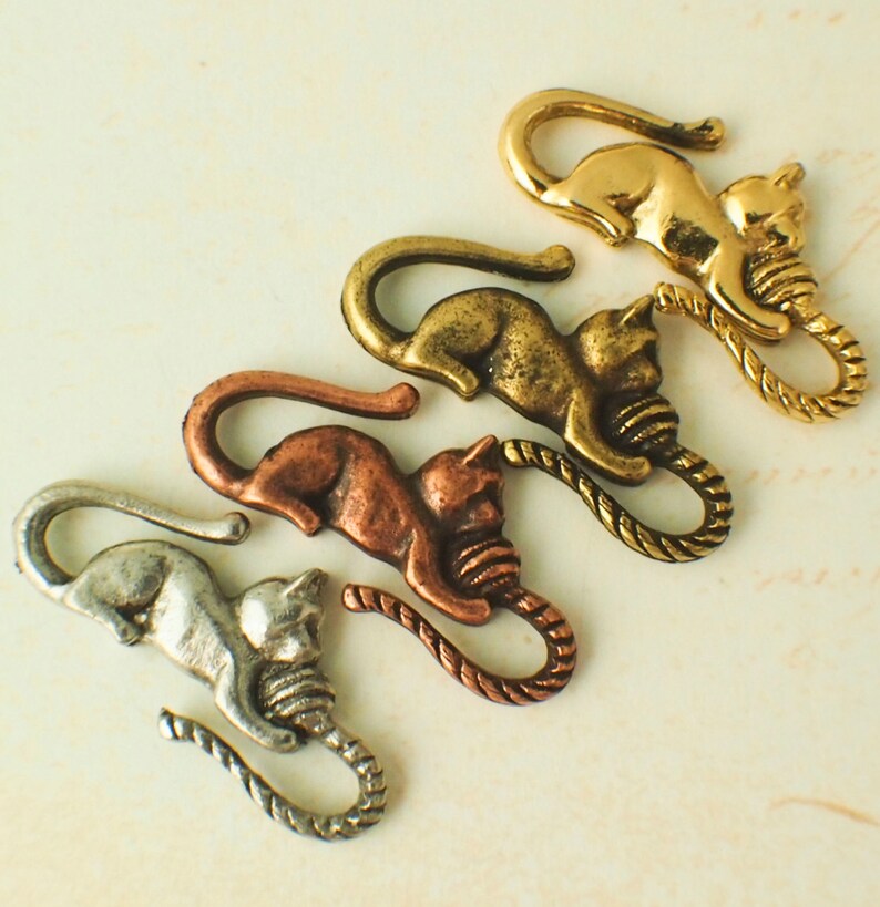 Puede incluir: Cuatro abalorios de gato de metal con un dise&ntilde;o de cuerda. Los abalorios son de plata, cobre, lat&oacute;n y oro.