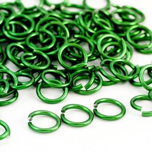 May include: A large pile of bright green metal jump rings. The rings are all the same size and are arranged in a random pattern.