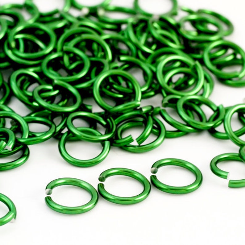 May include: A large pile of bright green metal jump rings. The rings are all the same size and are arranged in a random pattern.