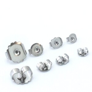 May include: Assortment of silver earring backs in various sizes and styles. The backs are made of metal and have a smooth finish.