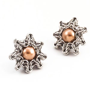 K&ouml;nnte beinhalten: Ein Paar silberne sternf&ouml;rmige Ohrringe mit einer braunen Perle in der Mitte jedes Sterns.
