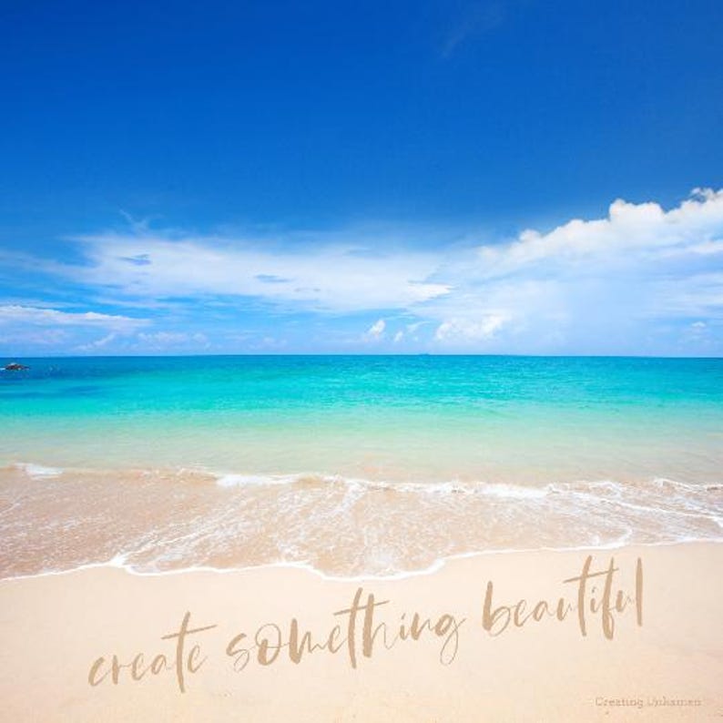 May include: A beach scene with blue sky, white clouds, and turquoise water. The sand is white and the waves are lapping at the shore. The text "create something beautiful" is written in the sand.