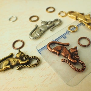 Puede incluir: Surtido de dijes de gato en plata, oro y cobre con un detalle de cuerda. Los dijes son perfectos para hacer joyas o para agregar un toque &uacute;nico a las manualidades.
