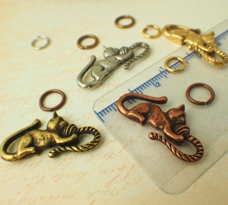 Puede incluir: Surtido de dijes de gato en plata, oro y cobre con un detalle de cuerda. Los dijes son perfectos para hacer joyas o para agregar un toque &uacute;nico a las manualidades.
