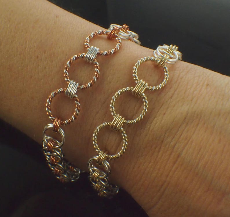 May include: Two chainmaille bracelets featuring interlocking circular links. One bracelet combines copper and silver-toned twisted wire rings, while the other bracelet features gold-toned and silver-toned twisted wire rings in a repeating pattern.