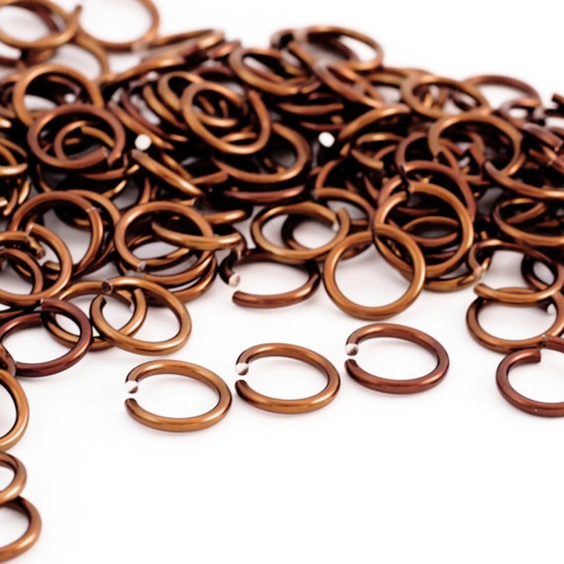 May include: A pile of small, copper-coloured jump rings. The rings are all the same size and are arranged in a random pattern.
