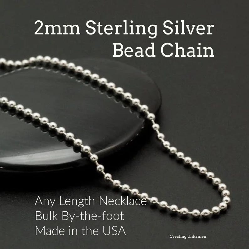 May include: A silver bead chain necklace made in the USA. The chain is 2mm in diameter and is available in any length. The necklace is shown on a black surface.