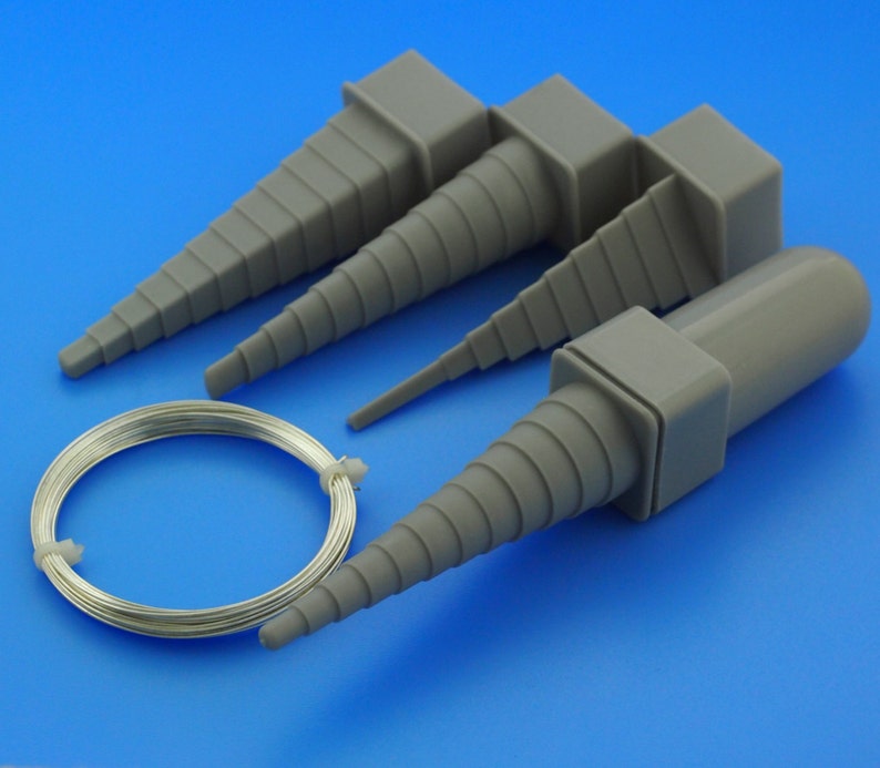 May include: Four grey plastic tapered tools for shaping wire, with a coil of silver wire in the centre.