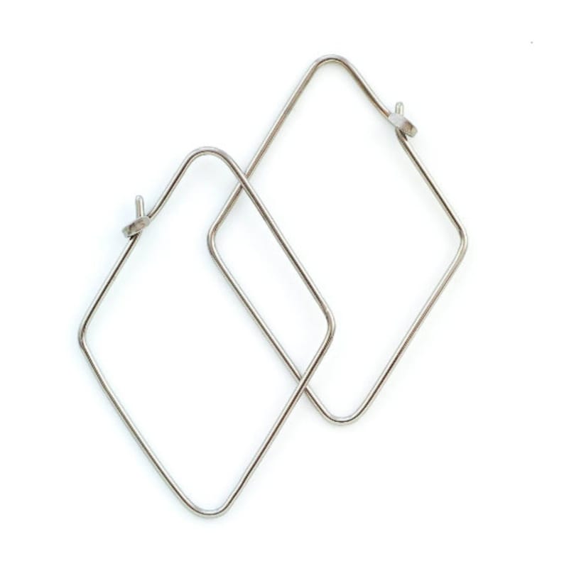 May include: A pair of silver square hoop earrings. The earrings are made of thin metal and have a simple, modern design.