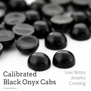 May include: Close-up of black onyx cabochons, also known as black onyx cabs, on a white surface.  The cabs are round and polished.  The text "Calibrated Black Onyx Cabs" and "Low Stress Jewelry Creating" is visible in the image.