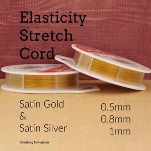 May include: Two white plastic spools of Elasticity Stretch Cord in satin gold and satin silver. The text on the image reads Elasticity Stretch Cord, Satin Gold & Satin Silver, and lists the available thicknesses as 0.5mm, 0.8mm, and 1mm.