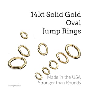 Puede incluir: Se muestran varios anillos de salto ovalados de oro macizo de 14 quilates de varios tamaños sobre un fondo blanco. El texto dice "14kt Solid Gold Oval Jump Rings" y "Made in the USA, Stronger than Rounds."